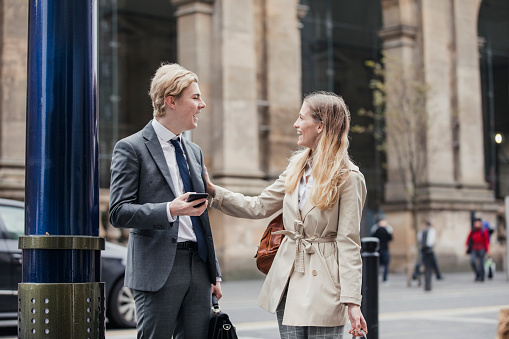 Businessman and businesswoman meeting up on the street to go to a meeting together.