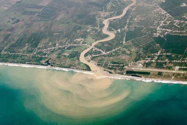 Top view from air, a bird's eye of the river with muddy water, flowing into ocean or sea. Top view from air, a bird's eye of the river with muddy water, flowing into ocean or sea. estuary stock pictures, royalty-free photos & images