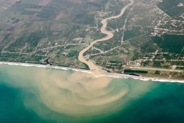 Photo of Top view from air, a bird's eye of the river with muddy water, flowing into ocean or sea.