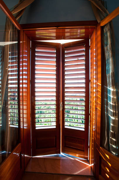 Closed wooden shutters on balcony window. Look from inside to outside. Colored inspiring vertical image. Part of italian architecture.