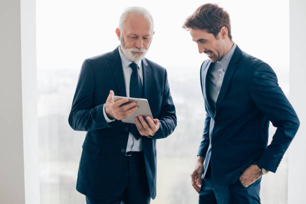 istock Senior man showing tablet to young coworker 960280450