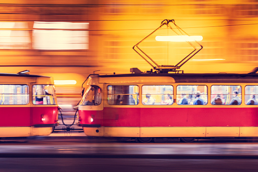 A Prague tram in motion in the city in the evening.