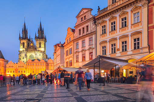 Tourists at old town square in Prague in the evening. On the left is the Church of Our Lady before Týn, a landmark of the area.