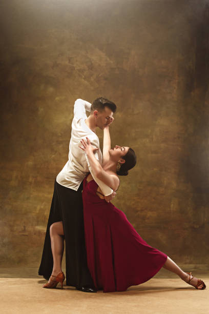 Dance ballroom couple in red dress dancing on studio background The young dance ballroom couple in red dress dancing in sensual pose on studio background. Professional dancers dancing tango. Ballroom dance concept. Human emotions - love and passion tango dance stock pictures, royalty-free photos & images