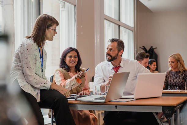 Business People Having a Meeting Co-workers talking though information on a laptop in a board room. Having a meeting in the conference. delegating stock pictures, royalty-free photos & images