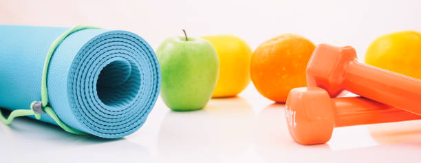 Yoga mat and dumbbells on white background