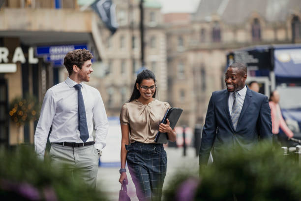 Successful Business Meeting Front view of three business people walking through the city streets. All three people are wearing formal clothing. colleagues outside stock pictures, royalty-free photos & images