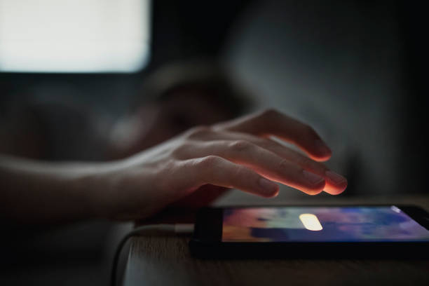 Hitting the Snooze Button Unrecognisable male going to touch the snooze button on his mobile phone. The alarm is waking him up in the morning. wake up man stock pictures, royalty-free photos & images