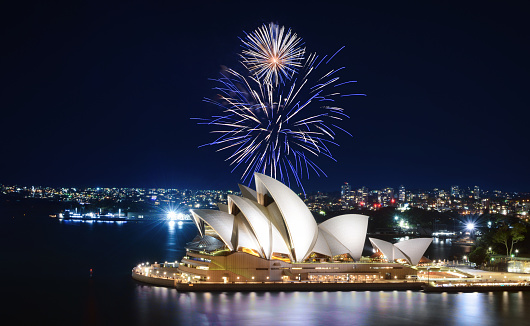 Sydney, Australia - March 8, 2018 - Blue and white fireworks explode in the sky over the Sydney Opera House in a dazzling spectacle of lights.
