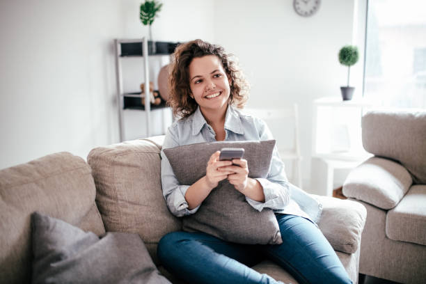 istock Woman uses cellphone on sofa at home 960301522