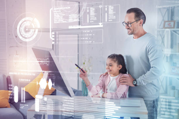 istock Clever pupil looking at the screen while her father standing behind her back 960316824