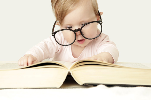 Adorable baby in front of big thick book, studio shot