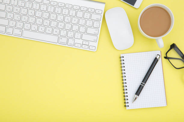 istock workspace with tablet, keyboard, coffee cup and eyeglasses copy space on yelow background. Top view. 960347970