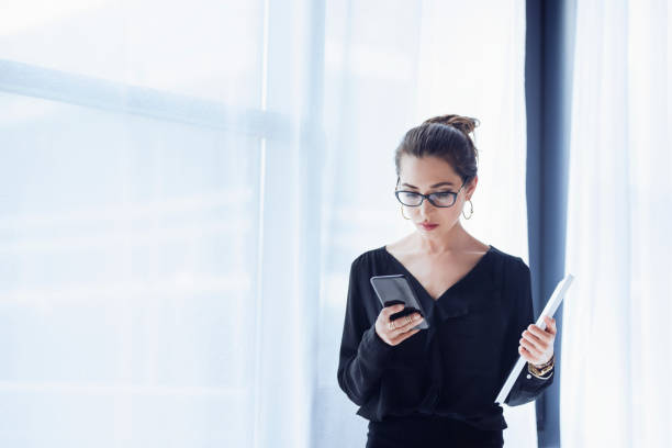 istock A young executive businesswoman checking her smart phone, standing in a modern working environment. Communicate about productivity, schedule, business, technology, smart phones, applications. 960349024