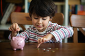 Kid put coin to piggy bank