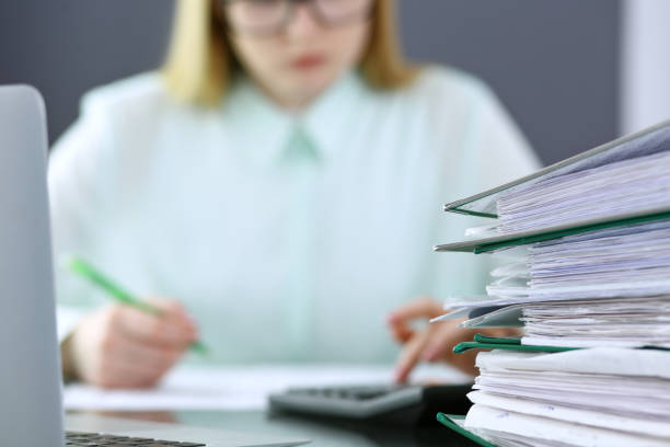 istock Bookkeeper or financial inspector  making report, calculating or checking balance. Binders with papers closeup. Audit and tax service concept. Green colored image backgroun 960353392