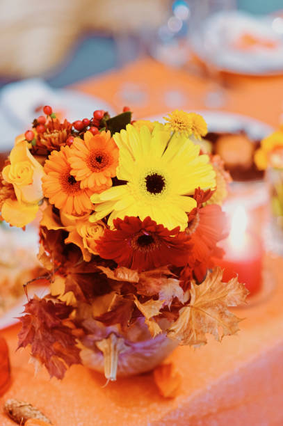 istock Autumn wedding decoration with flower composition with roses, chrysanthemum, maple leaves, pumpkin, books and candles. Haloween concept 960367324