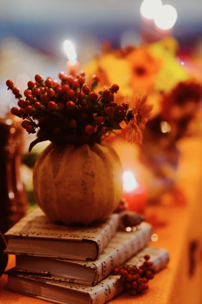 istock Autumn wedding decoration with flower composition with roses, chrysanthemum, maple leaves, pumpkin, books and candles. Haloween concept 960371380