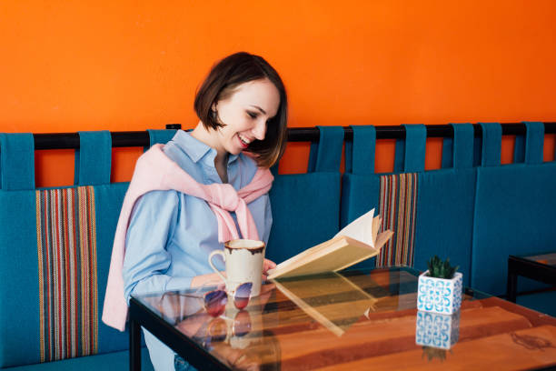 istock Woman drinking coffee and reading a book in a cafe 960382834