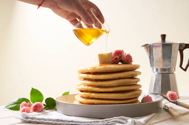 pancakes plate with honey and butter on the white table decorated with rose flowers - baking margarine studio shot macro imagens e fotografias de stock