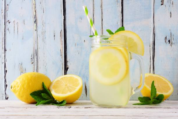 Lemonade in a mason jar glass with a blue wood background Homemade lemonade in a mason jar glass. Side view on a rustic blue wood background. mason jar lemonade stock pictures, royalty-free photos & images