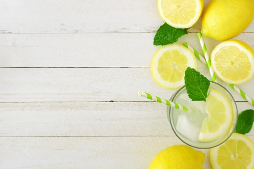 Sweet summer lemonade. Top view side border with copy space on a rustic white wood background.