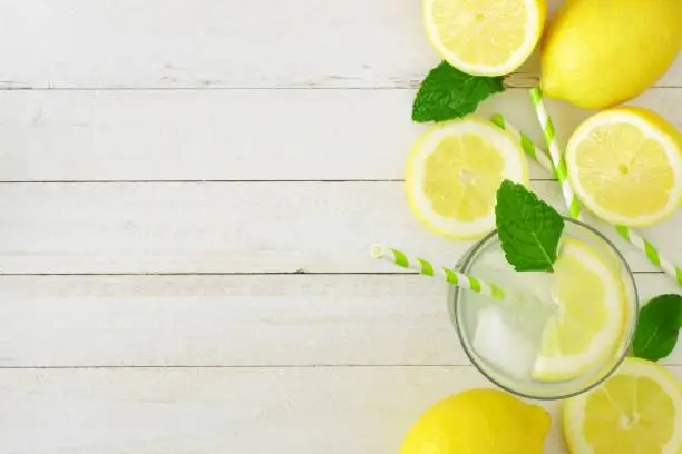 Photo of Summer lemonade, top view, side border on white wood