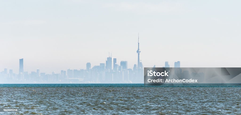 Foggy city skyline of Toronto on Lake Ontario. Distant city skyline silhouette of Toronto downtown in fog and mist with wavy water of Lake Ontario in foreground. Toronto Stock Photo