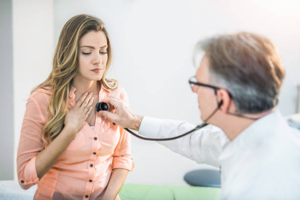 Young woman getting her painful chest examined by a doctor. Young woman getting her painful chest examined by a doctor. bronchitis stock pictures, royalty-free photos & images