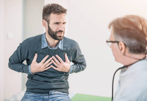 paziente maschio adulto medio che descrive un dolore toracico al suo medico. - male doctor foto e immagini stock