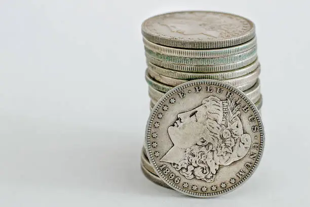 1896 Morgan Dollar coin is leaning on a stack of other Morgans.