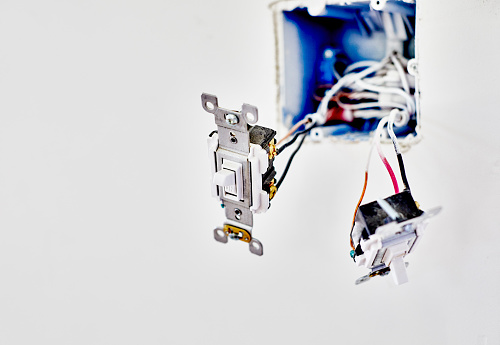 Two new light switches hanging from wires while being installed in new home construction