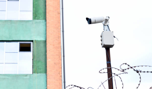 istock Camera video surveillance on the building background mounted on a brick wall, fenced with barbed wire 960448748