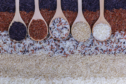 Food background with top view of five rows of rice in a wooden spoon.