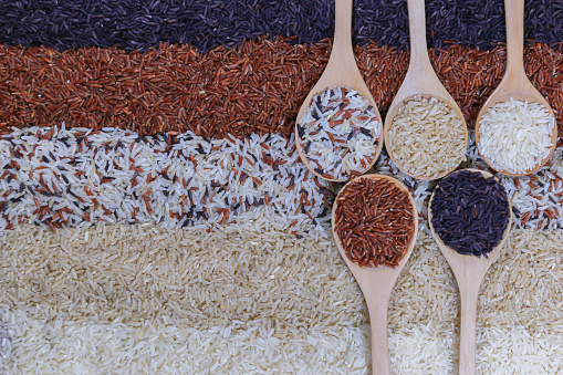 Food background with top view of five rows of rice in a wooden spoon.