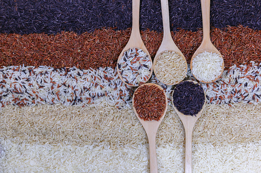 Food background with top view of five rows of rice in a wooden spoon.