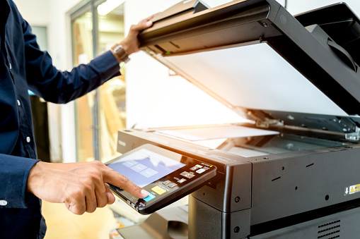 Bussiness man mano Presione el botón en el panel de la impresora, impresora escáner oficina copia láser suministra el concepto de inicio. photo