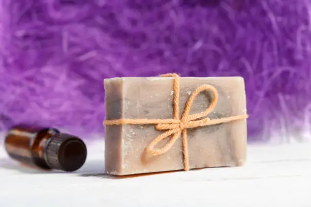 Natural soap with essential oil, on a violet background, lie on a white wooden table. Copy space
