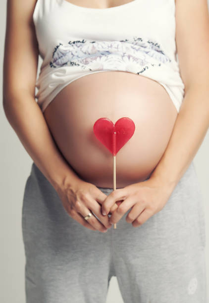 istock Pregnant woman holds red heart candy. 960466864