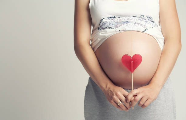 istock Pregnant woman holds red heart candy. 960471274
