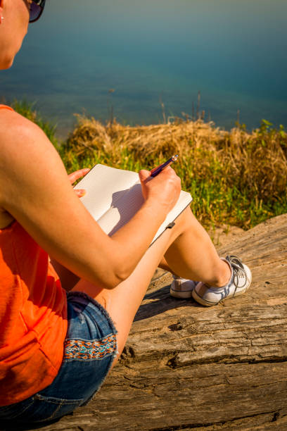 istock young woman sitting at a lake and writing in her diary 960480994