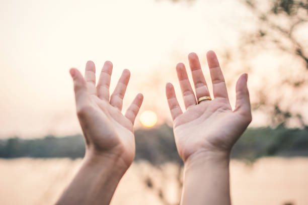 istock Human hands praying on nature during sunset,  hope and wish concept 960481284