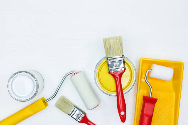 istock paint cans with rollers and brushes on white wooden background 960496332