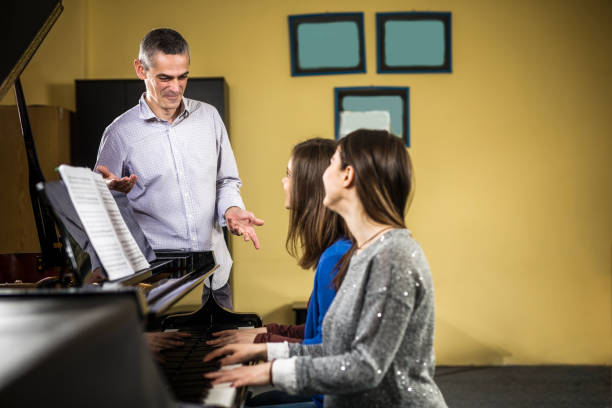 istock Two young woman perform piano duet for music teacher 960497614