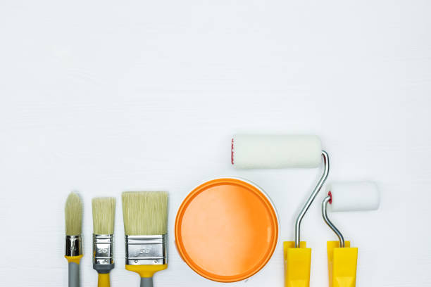 istock various paintbrushes and rollers, can of orange paint on white wooden background 960497636