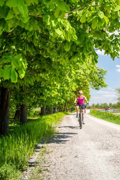 Woman cycling a mountain bike in a city park, summer day. Inspire and motivate concept for outdoors activity. Girl cyclist smiling and riding bicycle on a dirt road.