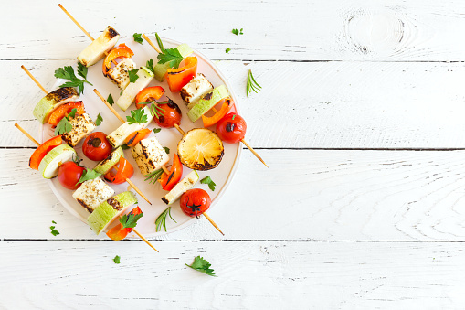 Vegetarian grilling. Vegetarian skewers with halloumi cheese and vegetables on white background, copy space.