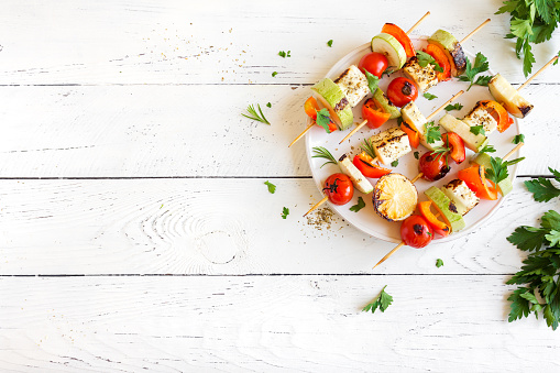 Vegetarian grilling. Vegetarian skewers with halloumi cheese and vegetables on white background, copy space.