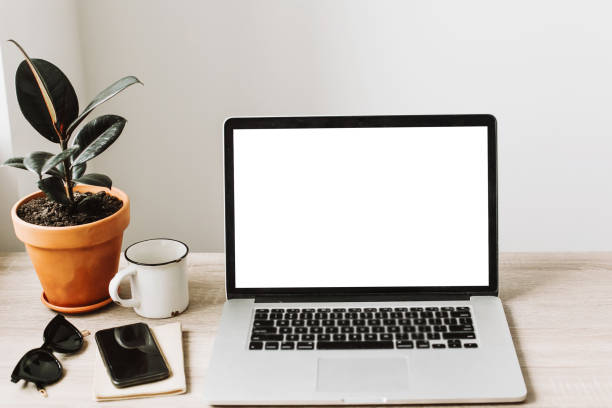 istock Laptop with empty screen on wooden desktop with phone, notebook, coffee and plant. space for text. mock-up. business workspace. working online home. Freelance concept. 960516496