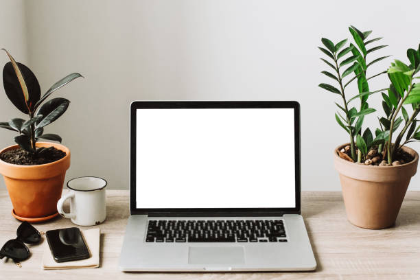 istock Freelance concept. Laptop with empty screen on wooden desktop with phone, notebook, coffee and plant. space for text. mock-up. business workspace in home or office 960516624